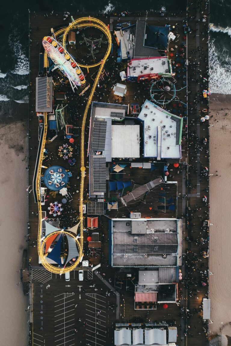 Drone view of the vibrant Santa Monica Pier amusement park, capturing lively rides and crowds.